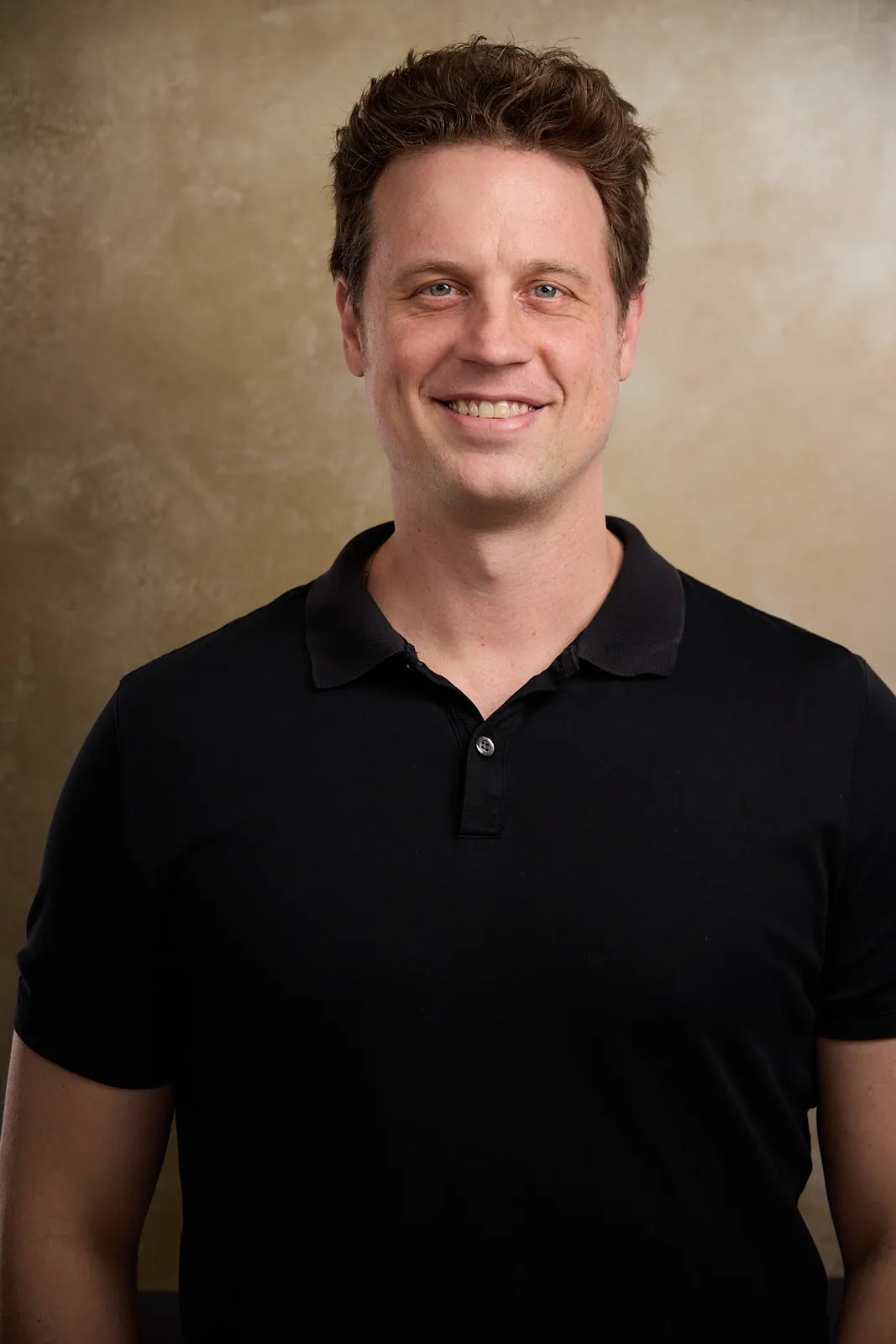 portrait of a man in a black shirt smiling
